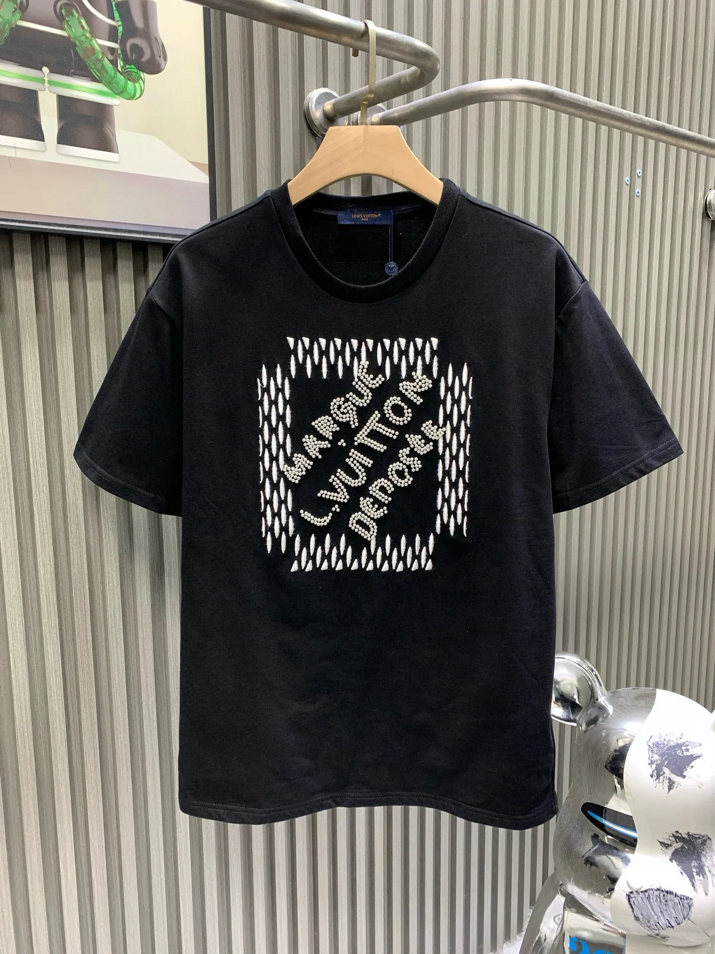 🅿️280 🀄️ Louis Vuitton Louis Vuitton 1V Louis Vuitton 2025FW The most expensive embroidered/pearl beaded half-sleeved T-shirt in history. This cotton T-shirt is from the 2025 spring and summer show. It shows the latest designer Pharrell Williams/Fei Dong's Marque L. Vuitton déposée logo created by citing the brand archives. Beaded embroidery and delicate silk threads highlight the dandy theme of the season. The reverse-effect beaded embroidered label injects a trendy look into the casual look. The fabric is made of 40s double-ply combed cotton + long-staple cotton blended compact siro-spun yarn. The weight is 280g. The front panel is embroidered with Tajima embroidery machine imported from Japan. Thick rubber pad base polyester mercerized three-dimensional hemming embroidery. Each bead is hand-pointed. A cardboard mold is opened. A single cut piece is powder-swept for precise positioning. The beads are made with 4-mile round pearlescent white bubble beads and are hand-crocheted. All single beads are tied with hooks and threads to ensure they are in the right position to sweep the powder, which is different from the ordinary beaded versions on the market.